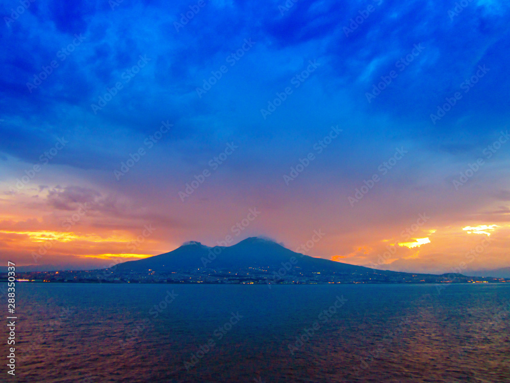 Evening view of Mount Vesuvius and Naples, Italy. Panoramic landscape with city Napoli and famous mountain from sea at sunset.
