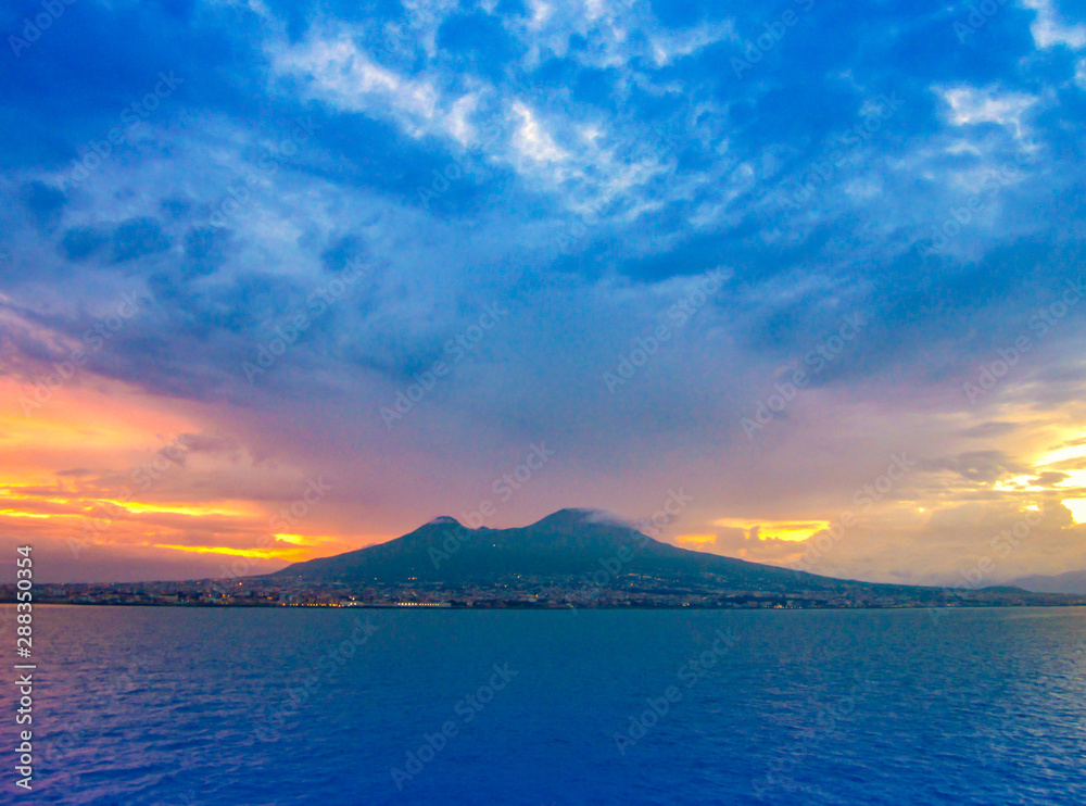 Evening view of Mount Vesuvius and Naples, Italy. Panoramic landscape with city Napoli and famous mountain from sea at sunset.