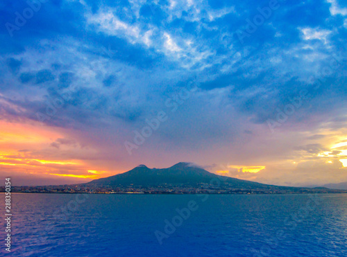 Evening view of Mount Vesuvius and Naples, Italy. Panoramic landscape with city Napoli and famous mountain from sea at sunset.