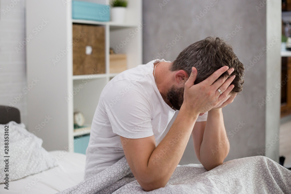Man waking up in his bedroom and rubbing his eyes.