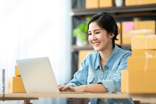 Happy asian entrepreneur woman smiling, checking order online and working by marketing online on computer laptop at home. Asain woman freelancer learning couse online by social media at workplace. photo