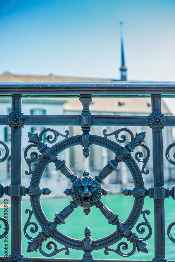 The ornated wrougth iron handrail on the Limmat riverside in Zurich with the Wasserkirche in the background  - 2