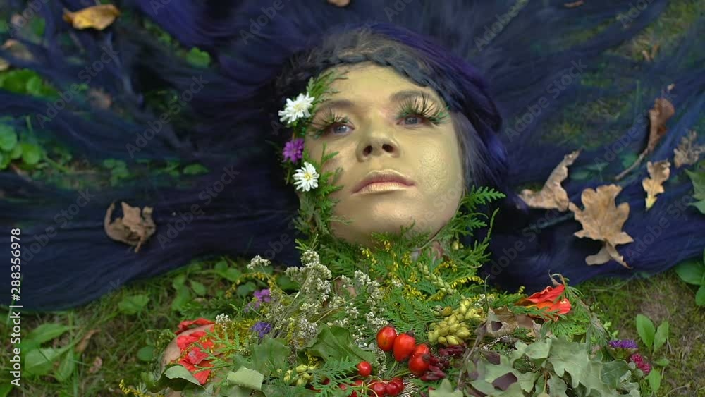 Earth mother in flowering decoration lying on grass, nature as living being