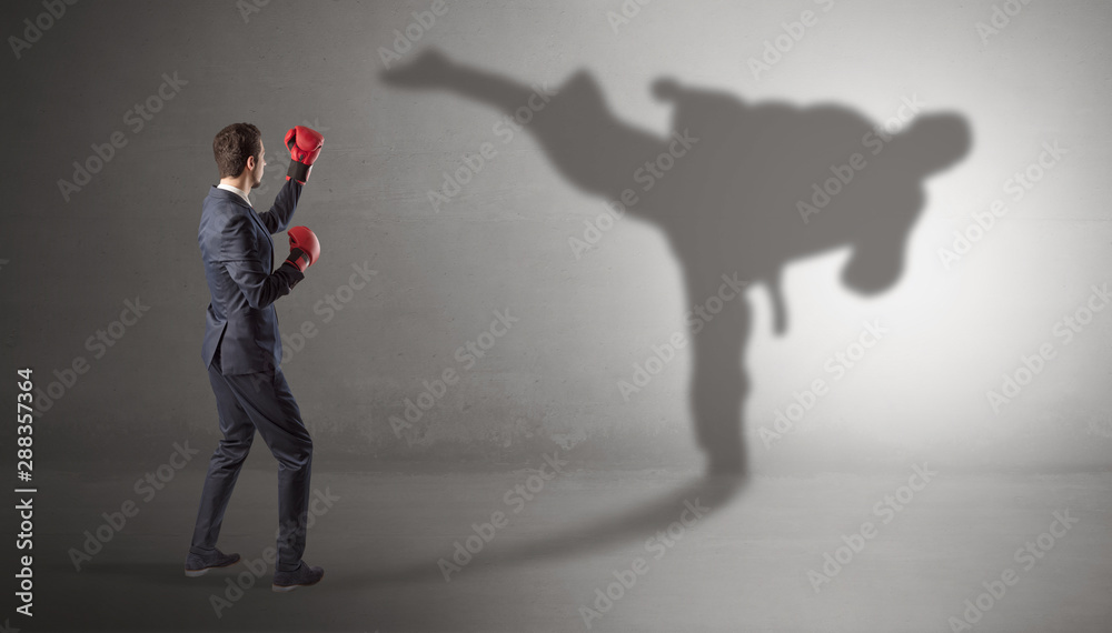 Fototapeta premium Businessman fighting with his strong karate man shadow
