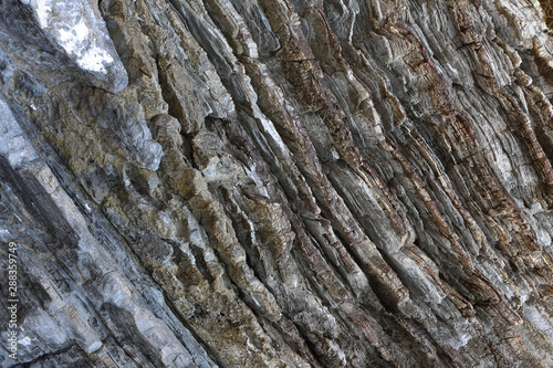Background on the basis of the texture of rock. Gray-brown stone texture with inclined weathered stripes