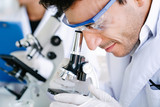 Scientist looking into microscope for checking medical test in science laboratory