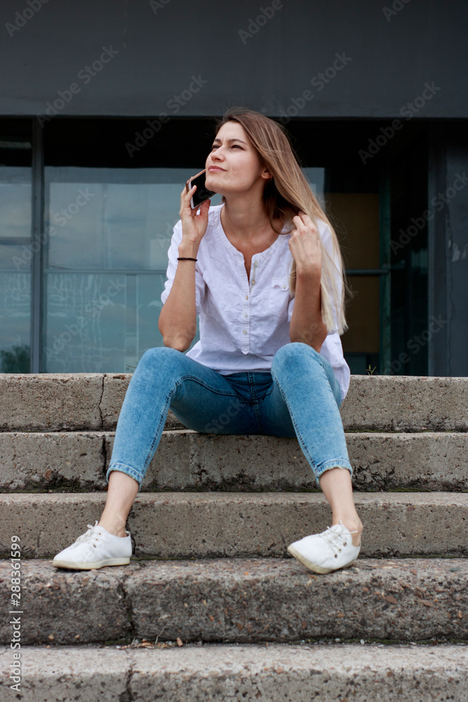 Girl in a white shirt on the steps of the university. The applicant is preparing for the school year. A student gets acquainted with an educational institution Girl in a white shirt on the steps of the university. The applicant is preparing for the school year. A student gets acquainted with an educational institution