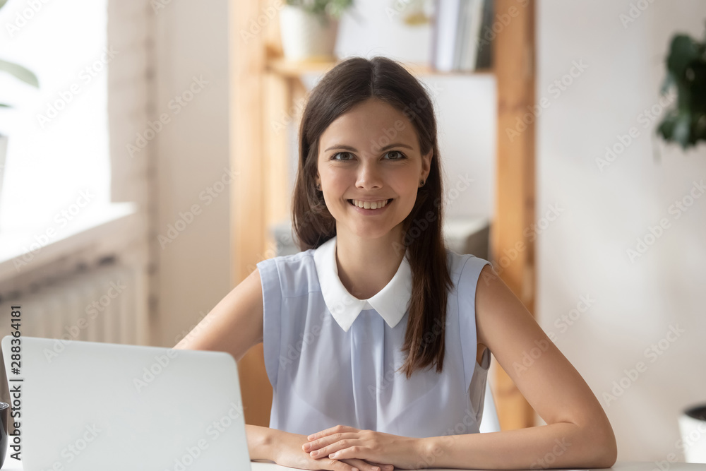 Portrait of smiling young woman posing for picture at workplace