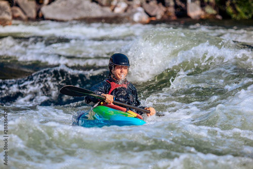 Obraz premium Guy in kayak sails mountain river. Whitewater kayaking, extreme sport rafting