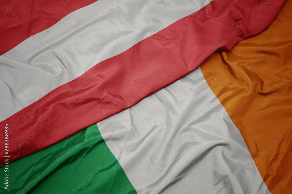waving colorful flag of ireland and national flag of austria.