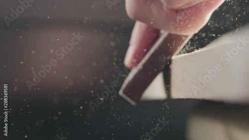 Slow motion woodworker hand sanding walnut board with sand block