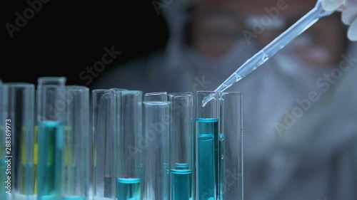 Researcher dripping chemical liquid into tube, analyzing substance properties