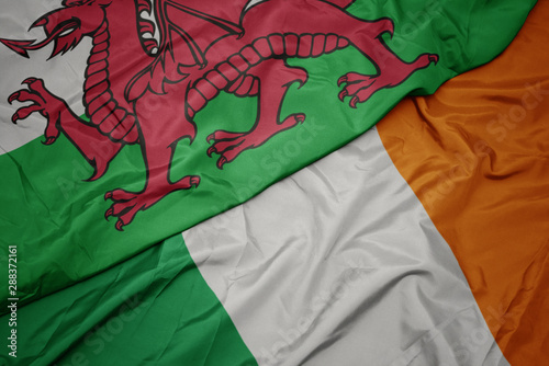 waving colorful flag of ireland and national flag of wales.