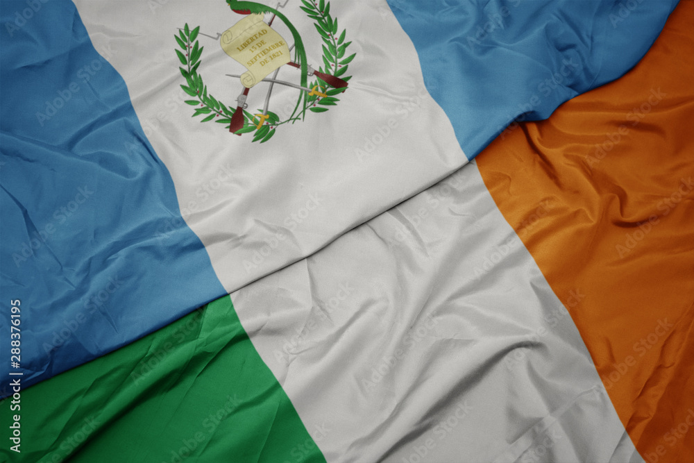 waving colorful flag of ireland and national flag of guatemala.