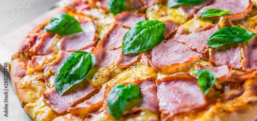 Pizza with Mozzarella cheese, ham, tomato sauce, pepper, Spices and Fresh basil. Italian pizza on wooden table background