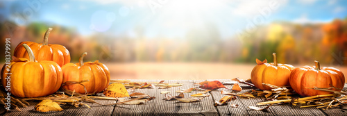 Thanksgiving Pumpkins And Leaves On Rustic Wooden Table With Sunlight And Bokeh On Autumn Background - Thanksgiving / Harvest Concept photo