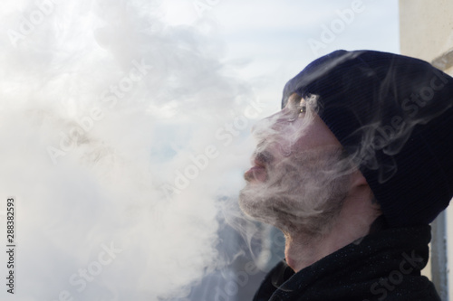 Chico joven vapeando rodeado de humo
