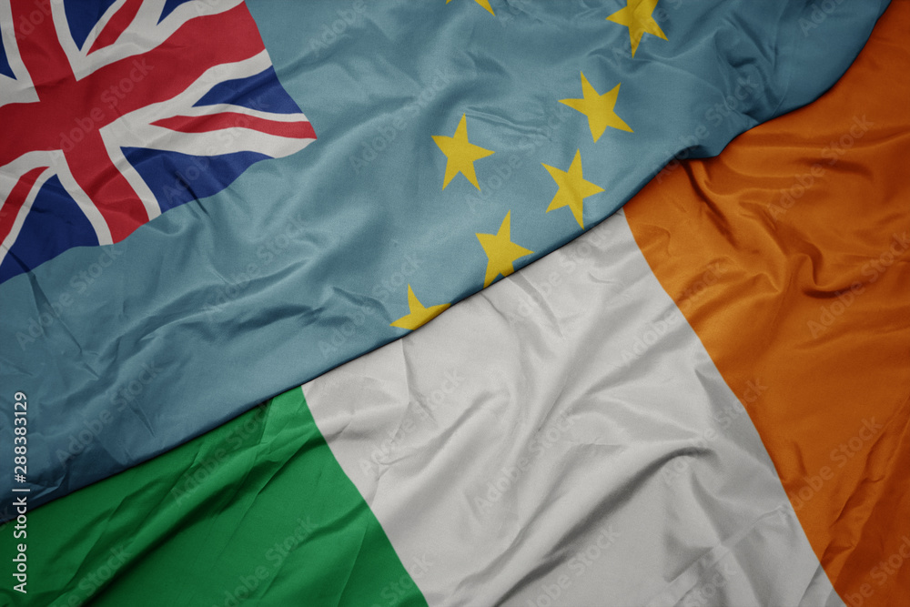 waving colorful flag of ireland and national flag of Tuvalu .
