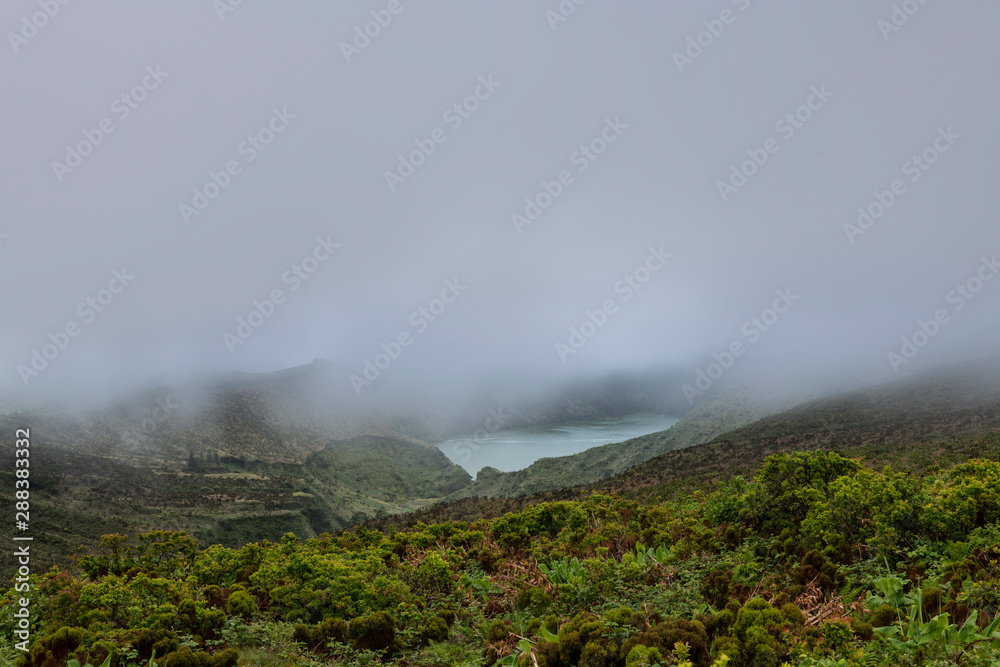 Landscape of low clouds and bad weather over Lagoa Funda das Lajes caldera volcanic crater lake at Ilha das Flores island in the Azores