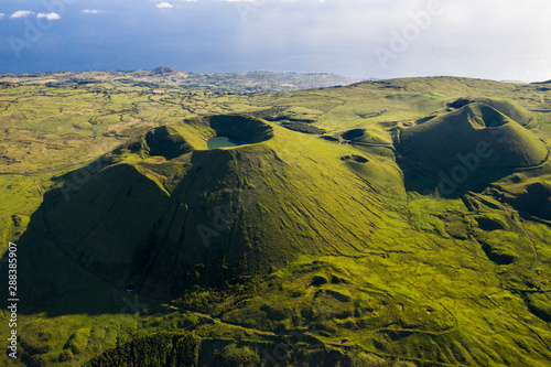 Aerial image of typical green volcanic caldera crater landscape with volcano cones of Planalto da Achada central plateau of Ilha do Pico Island, Azores photo
