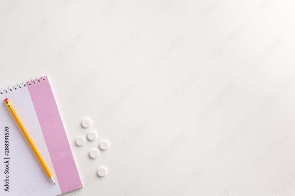 Notepad, pencil and pills on white background. Medical concept. Flat lay. Notepad, pencil and pills on white background. Medical concept. Flat lay.