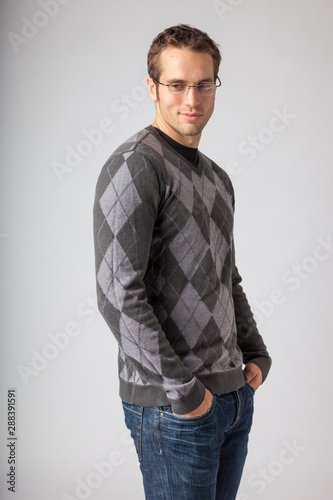 Man wearing argyle sweater, jeans and eyeglasses. Young men's casual clothing apparel styles. © ML Harris
