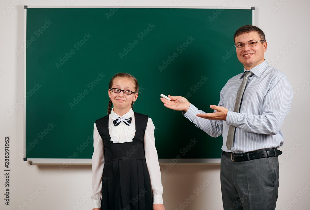 Portrait of a teacher and schoolgirl like as excellent pupil, posing at blackboard background - back to school and education concept Portrait of a teacher and schoolgirl like as excellent pupil, posing at blackboard background - back to school and education concept