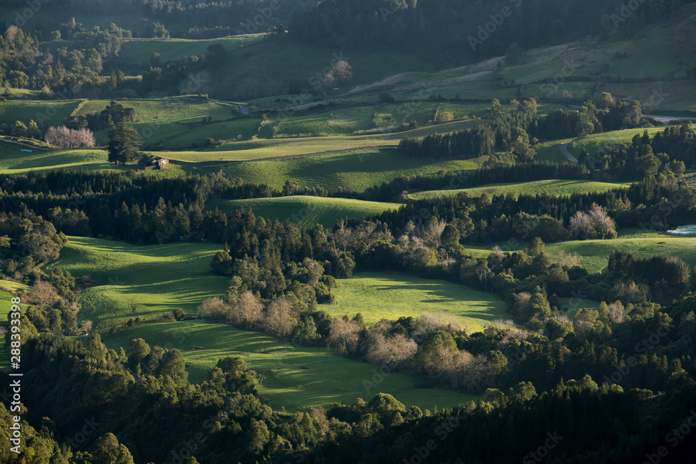 Obraz premium View on pastures at sunset from near Pico da Vara at Planalto dos Graminhais into the direction of the southeast coast valleys of Nossa Senhora dos Remédios and Povoação