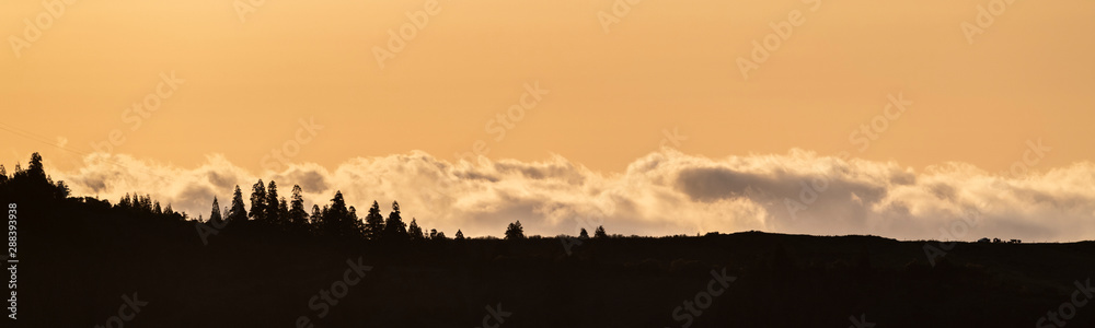 sunrise panorama behind the volcanic crater ridge of the Furnas caldeira on Sao Miguel island, with the silhouette of pine forests