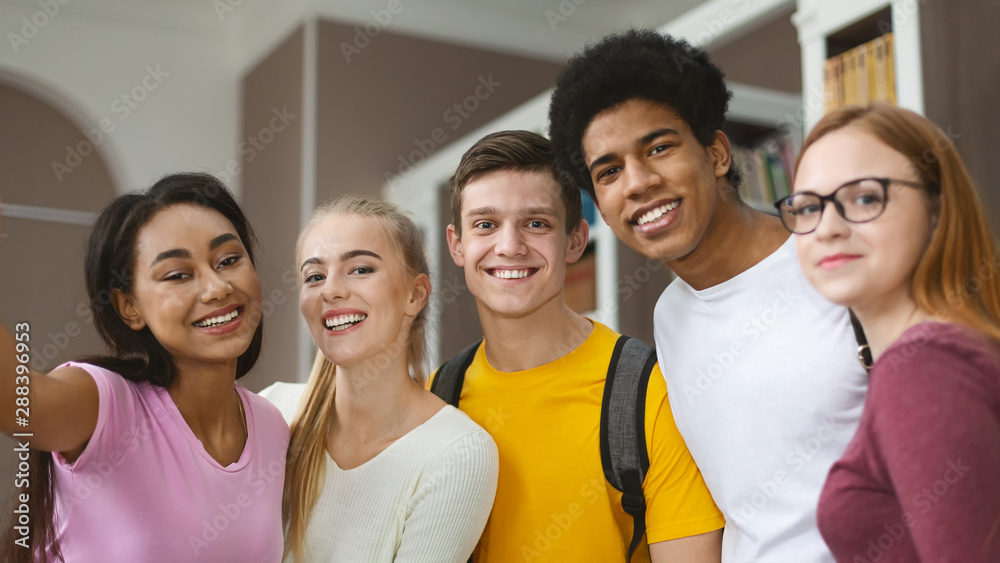 Happy multiracial young students taking selfie at library Happy multiracial young students taking selfie at library