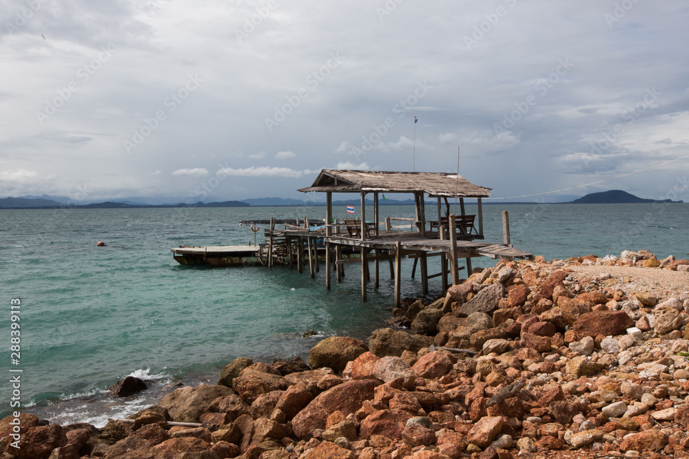 a rusty wooden boat dock on the rocky shore of Koh Talu Island near Hua HIn Thailand