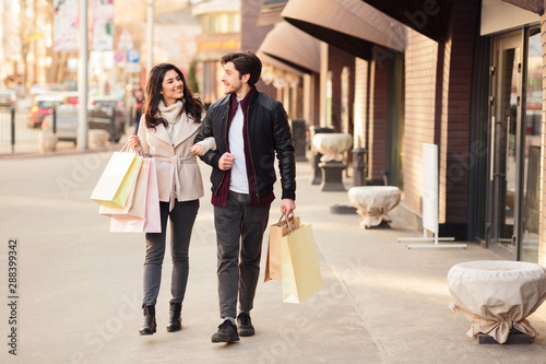Young happy couple with shopping bags walking outdoors