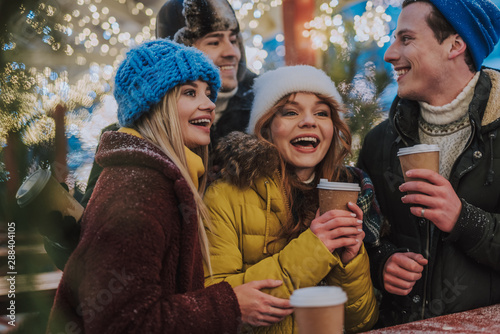 Positive delighted best friends drinking hot beverages