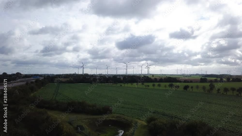 Aerial shot flyover a green field towards large wind farm in rural area of Germany. Aerial shot flyover a green field towards large wind farm in rural area of Germany.