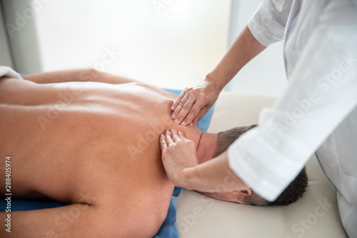 Female medic is doing shoulder massage fot man