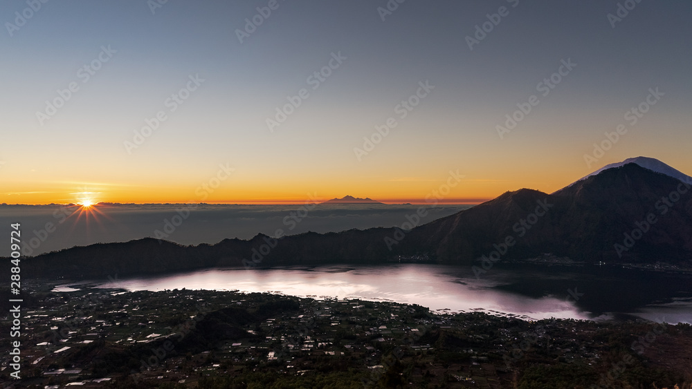 Stunning Sunrise from the top of Mt. Batur, Bali, Indonesia. In the right, across lake Batur, Mt Abang and Mt Agung. Central in the background, some peaks of Lombok.
