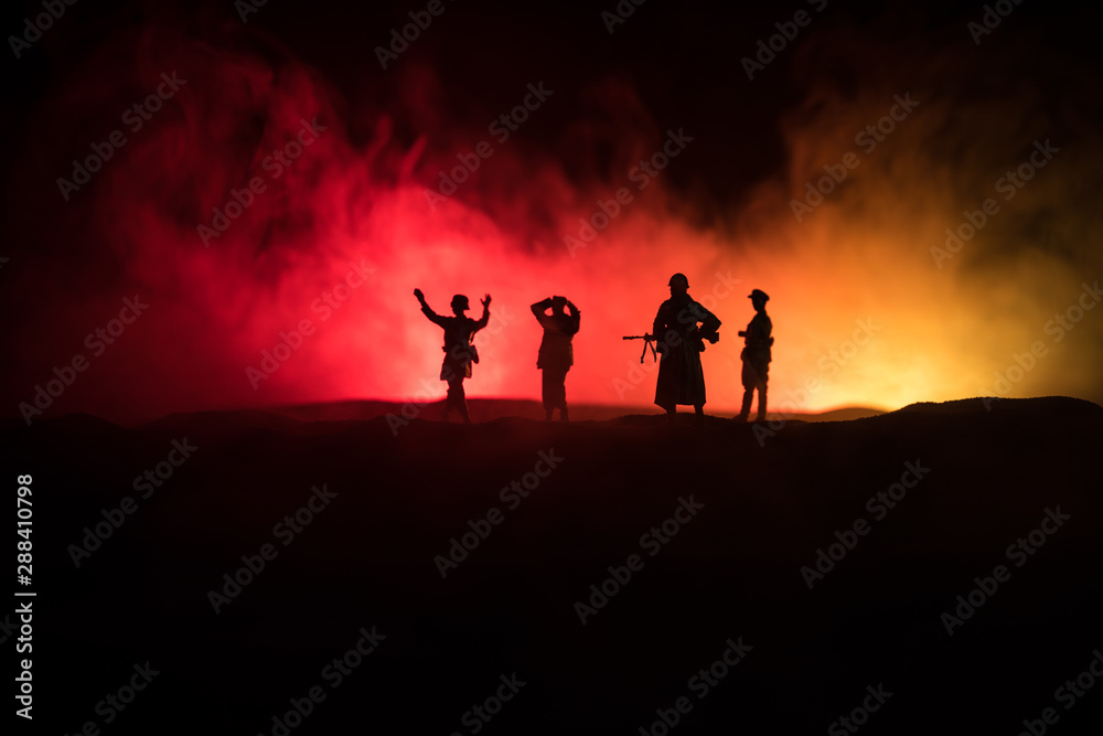 Battle scene. Military silhouettes fighting scene on war fog sky background. A German soldiers raised arms to surrender. Plastic toy soldiers with guns taking prisoner the enemy soldier.