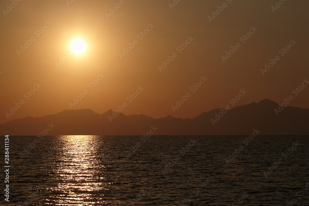 View from the yacht to the sun setting behind the mountains