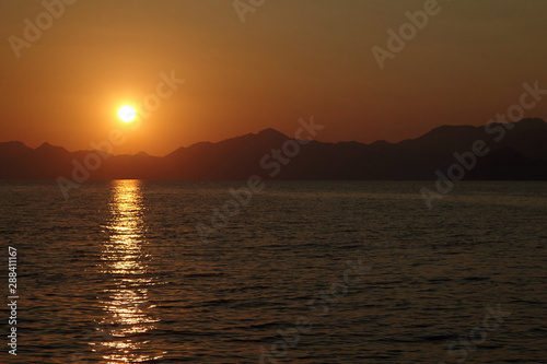 View from the yacht to the sun setting behind the mountains