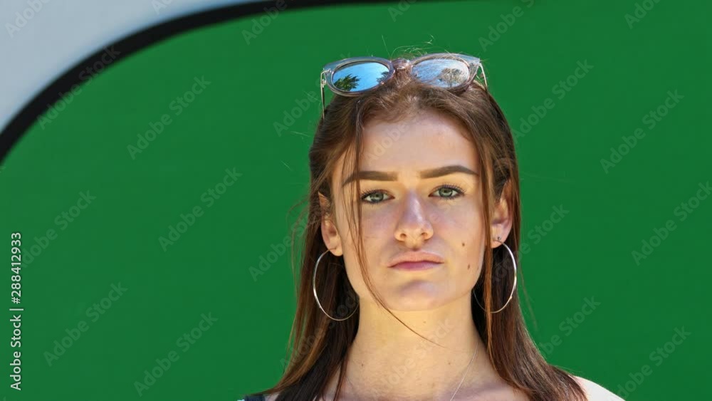 Girl laughing with sunglasses standing outside in front of a green screen