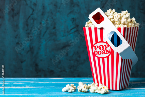 Popcorn bucket and 3D glasses with copy space on blue background