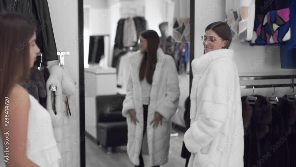 Polish woman trying out a winter collection coat with friend's validation, medium shot Polish woman trying out a winter collection coat with friend's validation, medium shot