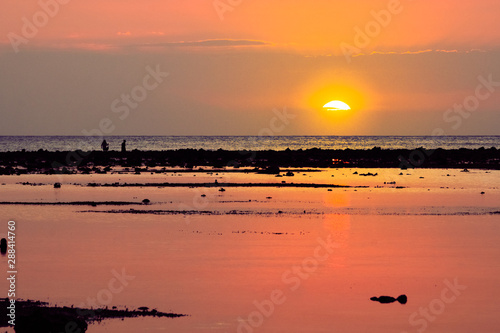 Sunset at west side of Gili Trawangan. Silhouette of people walking. Gili islands, Indonesia.