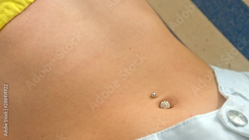 Girl with sporty belly with a navel piercing. Close Up