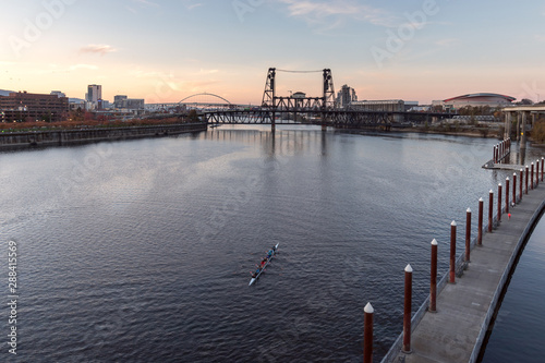 Willamette River at sunset with rowers in a boat in the foreground, Fremont, Broadway, and Steel Bridges in the background photo