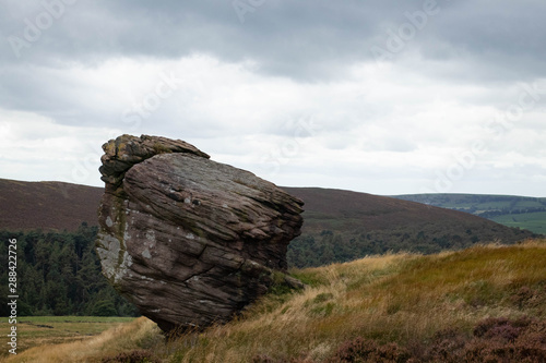 A big boulder standing in the Peak District with a moody sky behind it