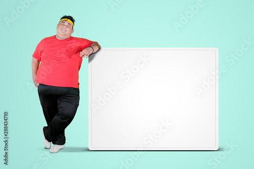 Overweight man leaning on a blank whiteboard photo