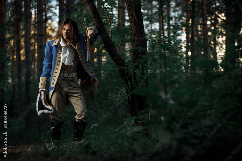 An 18th-century officer with pistol and sword stands by tree in forest An 18th-century officer with pistol and sword stands by tree in forest