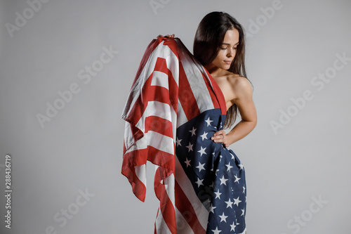 Beautiful woman wrapped in American flag on grey background. American Partiot Sexy Girl with USA flag photo