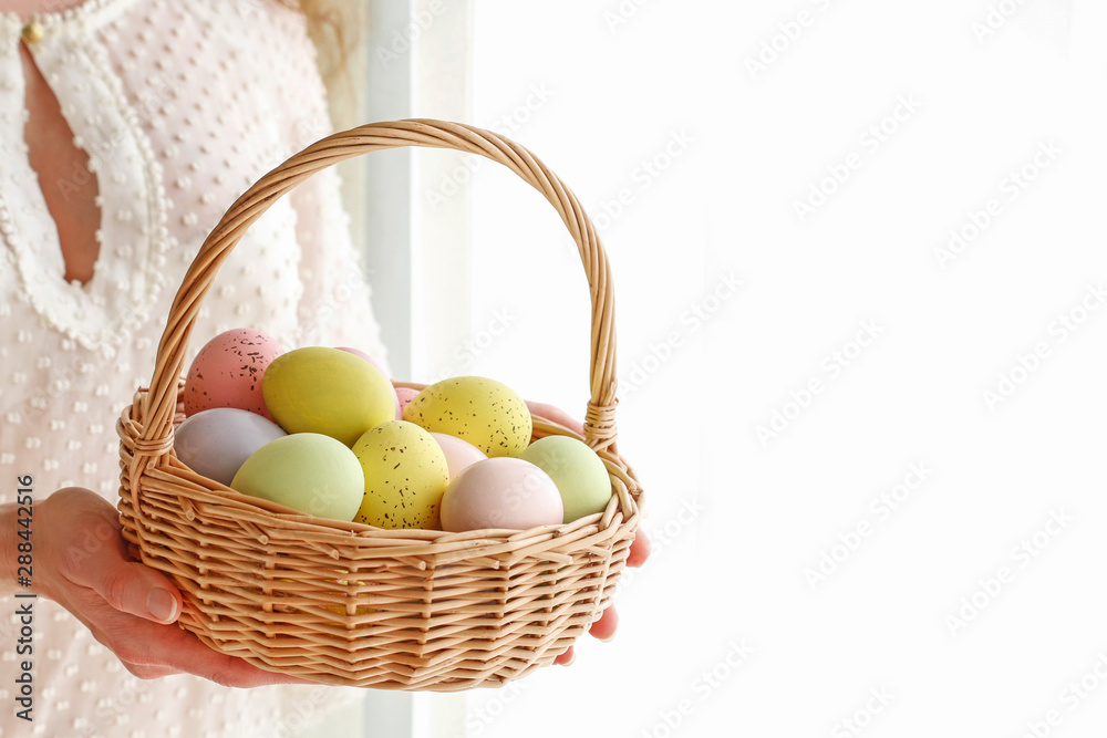 Woman holds a wicker basket with Easter eggs